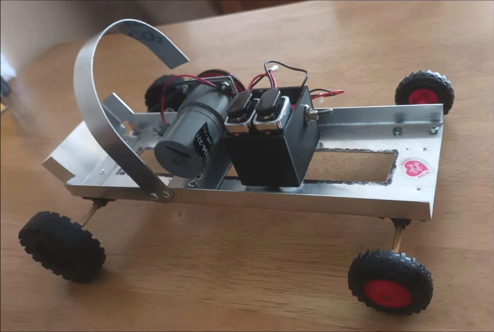 The finished hill-climb vehicle: an aluminium sheet chassis with a hollowed middle, a curved rear bottle support, motor and batteries, and four wheels.
